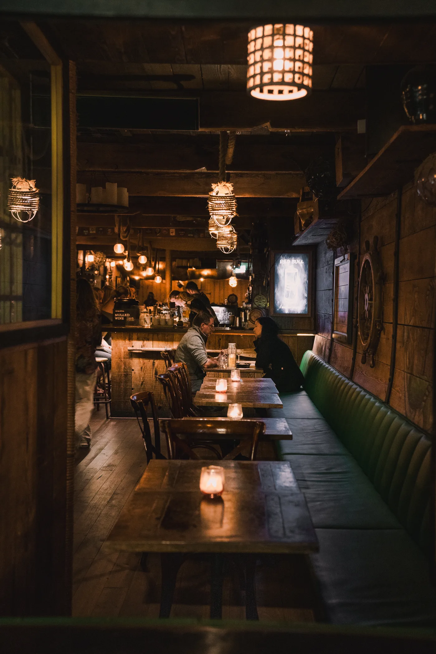Candlelit tables and green booth seating along the bar at The Hold, Manly
